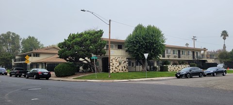 A street with cars and a building with a stone facade.