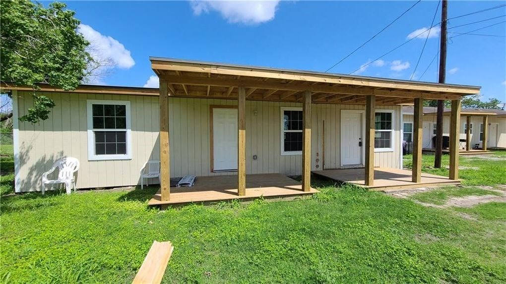 a small house with a porch and a lawn