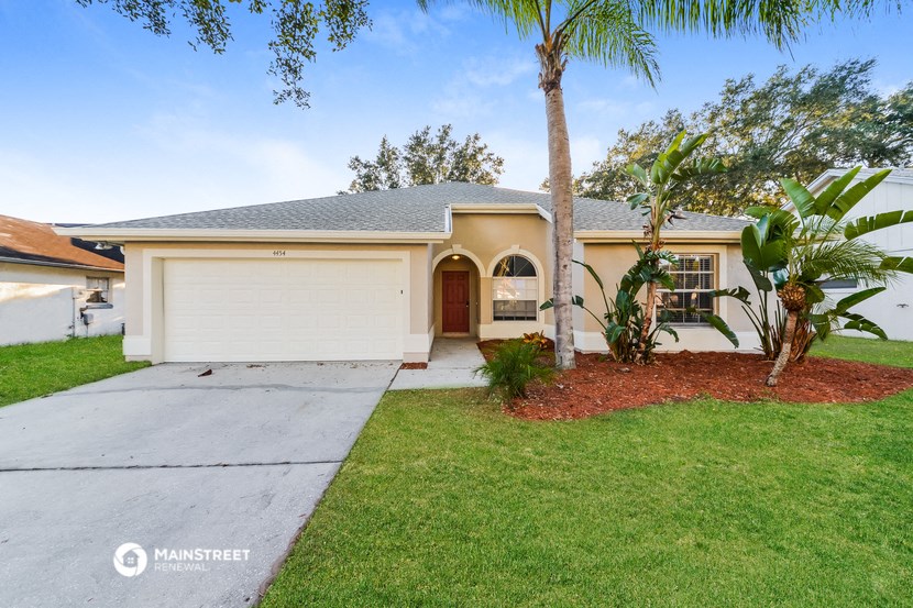 a yellow house with a sidewalk and palm tree