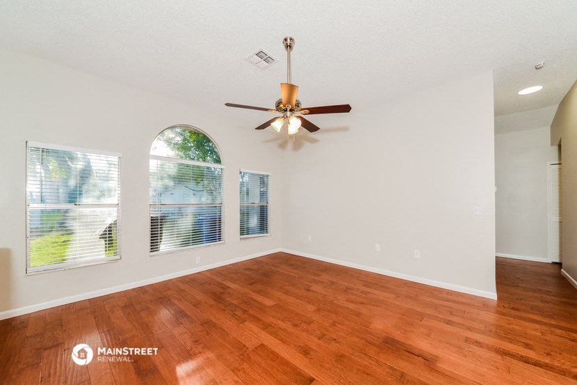 an empty living room with wood floors and a ceiling fan