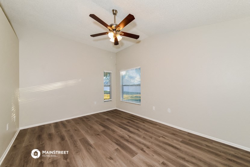 an empty living room with a ceiling fan and a window