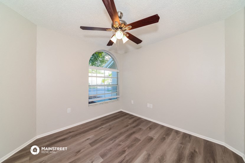 the living room has a large window and a ceiling fan