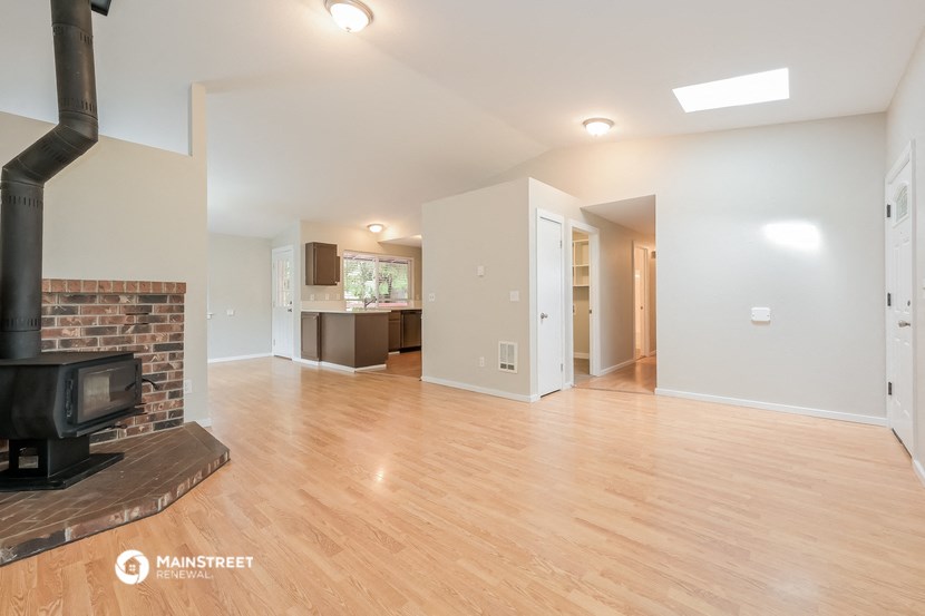 an empty living room with a fireplace and wood flooring