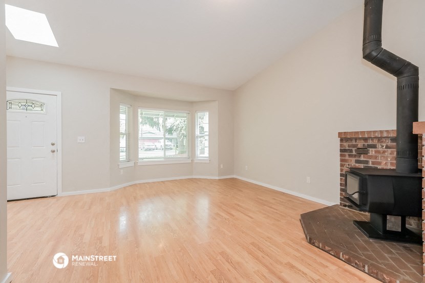 an empty living room with a fireplace and wood flooring
