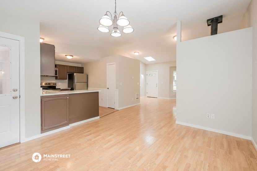 an empty living room and kitchen with a wood floor