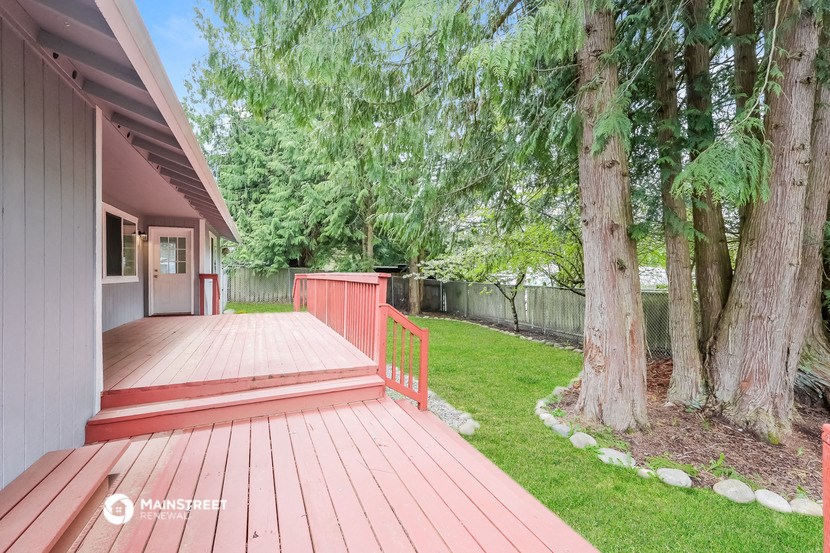 a backyard with a wooden deck and a tree