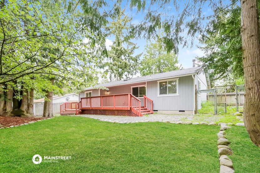 a white house with a red porch and a yard with trees