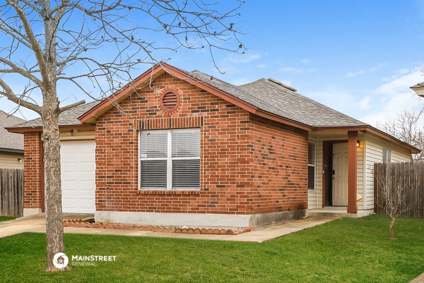 the front of a brick house with a yard and a tree
