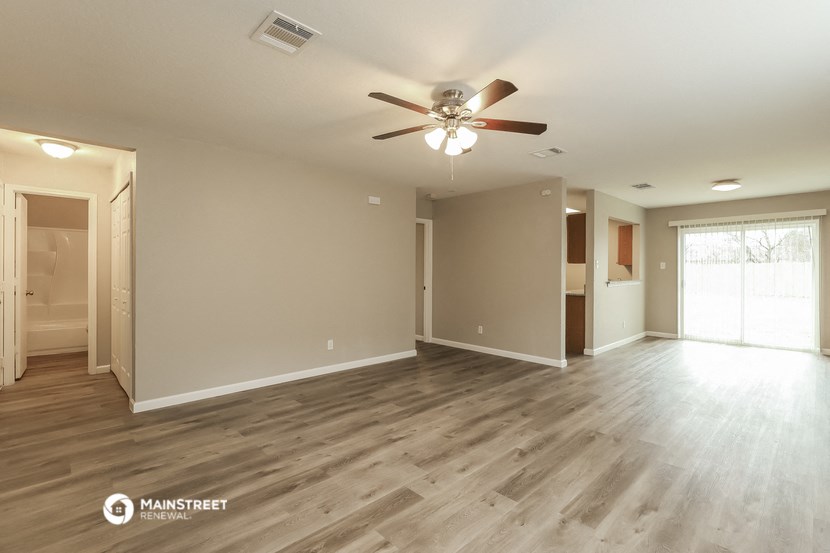 the spacious living room with hardwood floors and a ceiling fan