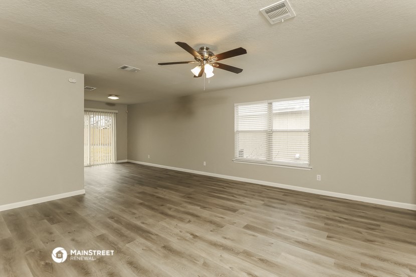 the spacious living room with hardwood floors and a ceiling fan