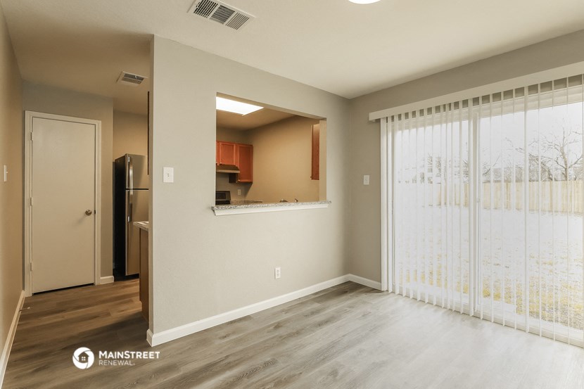 a living room with a large window and a door to a kitchen
