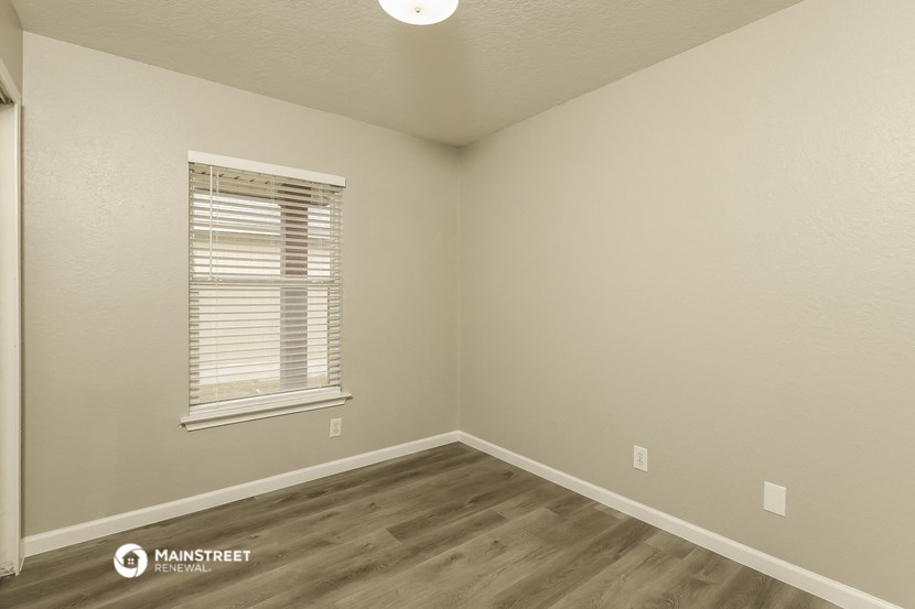 the interior of a bedroom with wood flooring and a window
