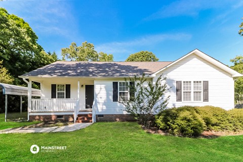 a small white house with a porch and a lawn