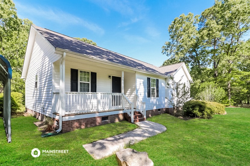 a small white house with a porch and a grassy yard