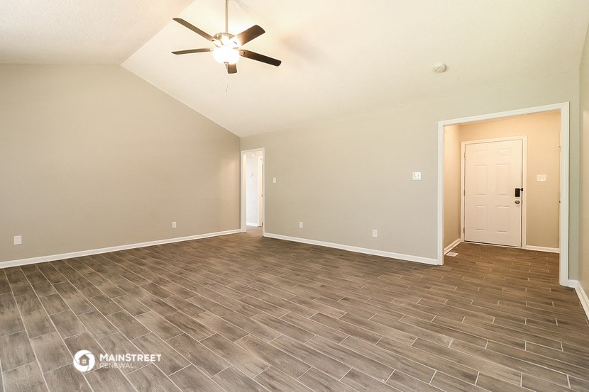 the spacious living room with vinyl flooring and a ceiling fan