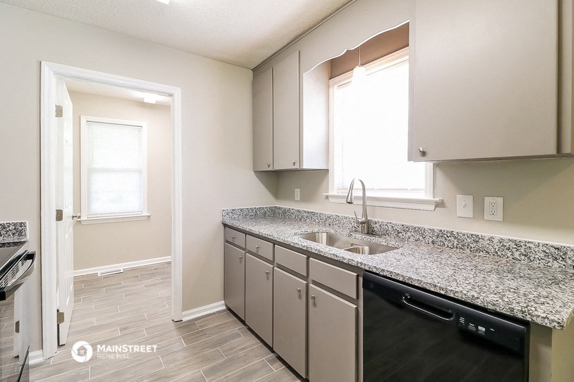 an empty kitchen with granite counter tops and a sink