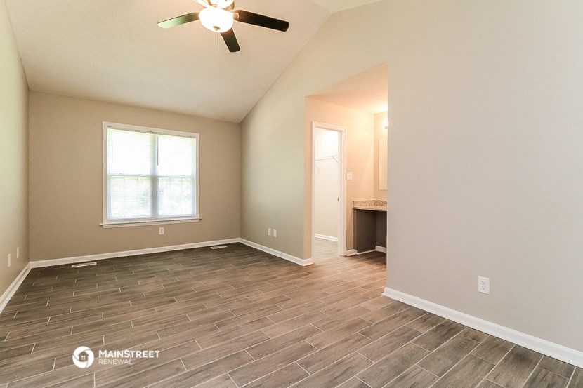 the spacious living room with wood flooring and a ceiling fan