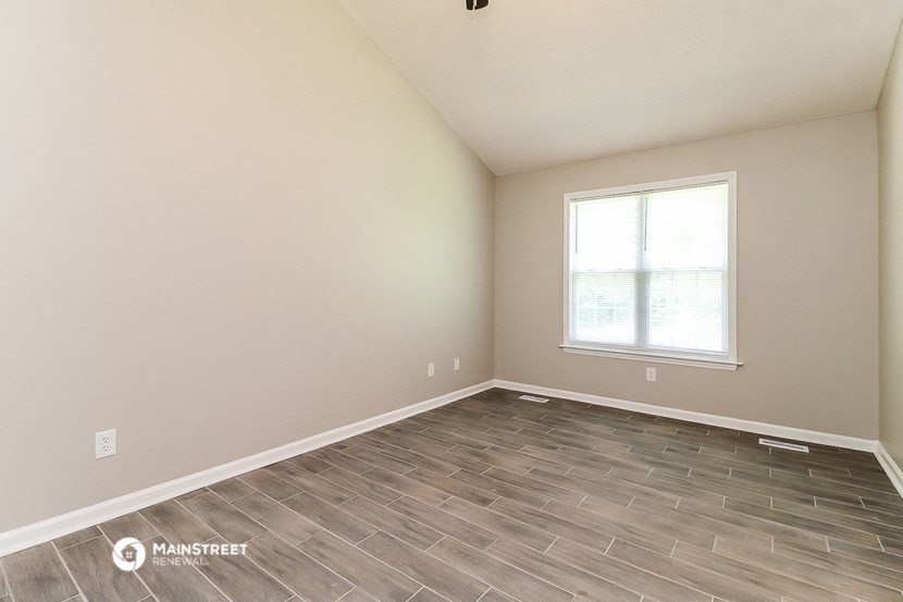 the spacious living room with wood flooring and a window