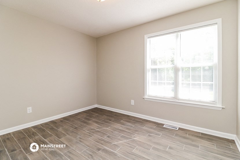 the spacious living room with a large window and wood flooring