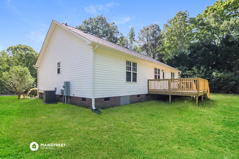 a small white house with a wooden deck on the side