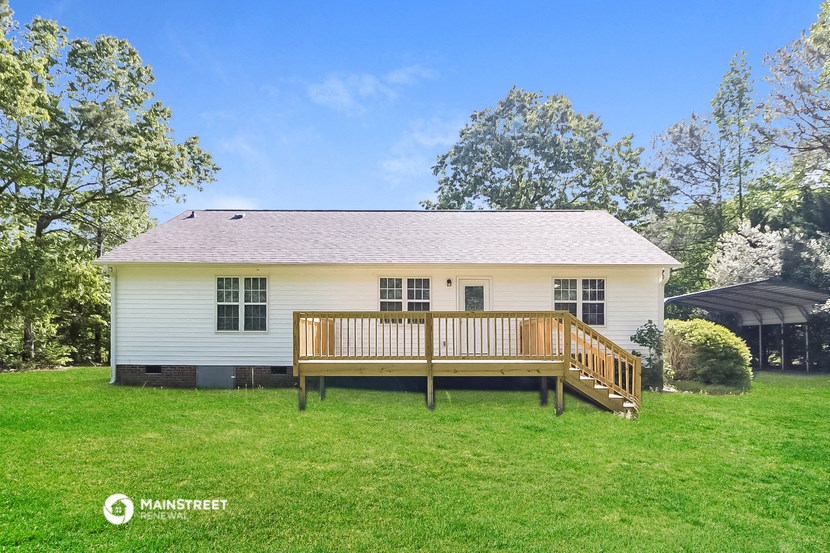 a small white house with a wooden deck in front of it