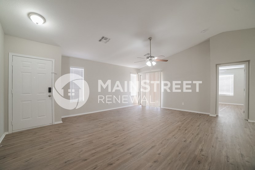 a large living room with a hard wood floor and a ceiling fan