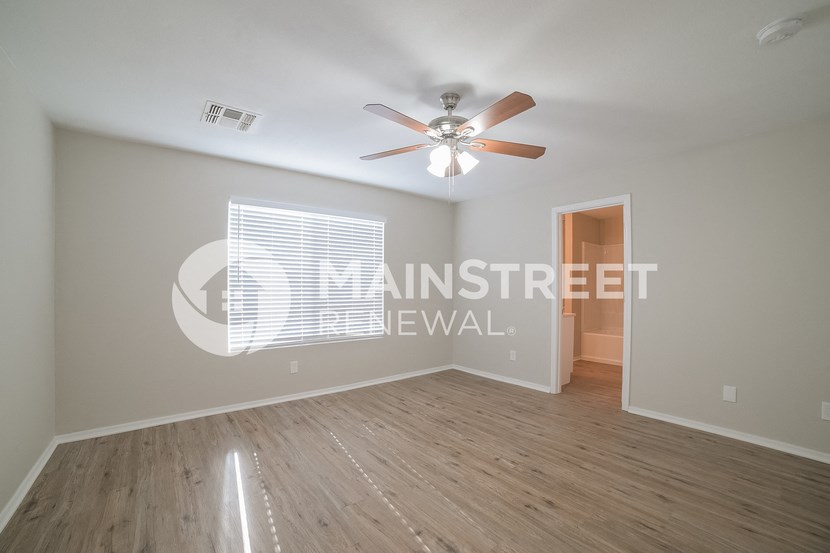 a living room with a ceiling fan and a hard wood floor