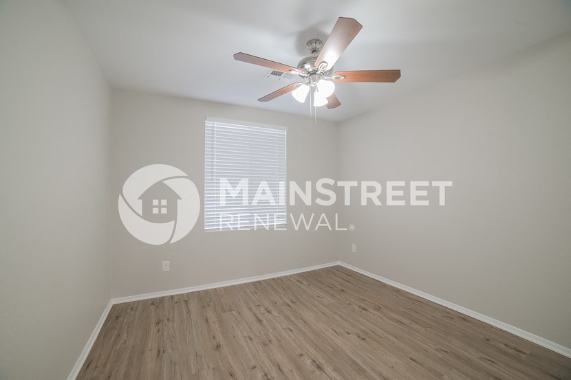 a spacious living room with a ceiling fan and a window