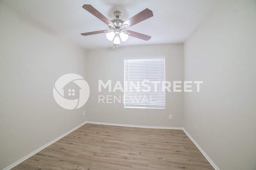 a bedroom with a hard wood floor and a ceiling fan