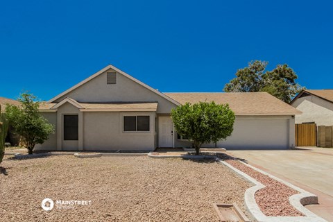 a white house with a driveway and a tree in front of it