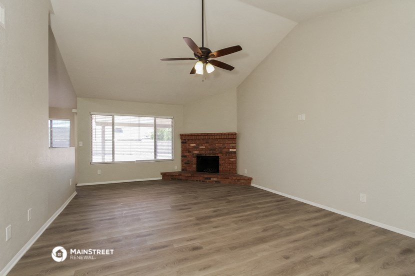 the spacious living room with fireplace and ceiling fan