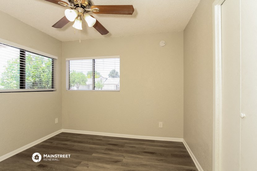 an empty living room with a ceiling fan and a window