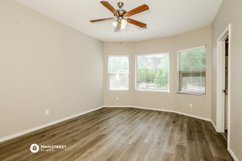 the spacious living room with hardwood floors and a ceiling fan