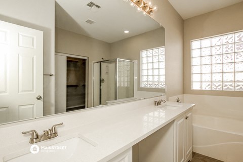 the master bathroom has a large mirror and a dual sink