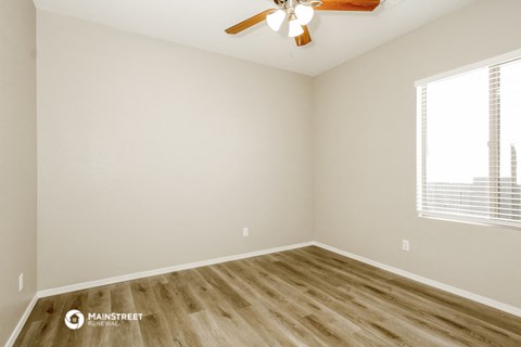an empty room with wooden floors and a ceiling fan