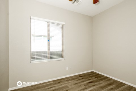 a bedroom with a window and wood flooring