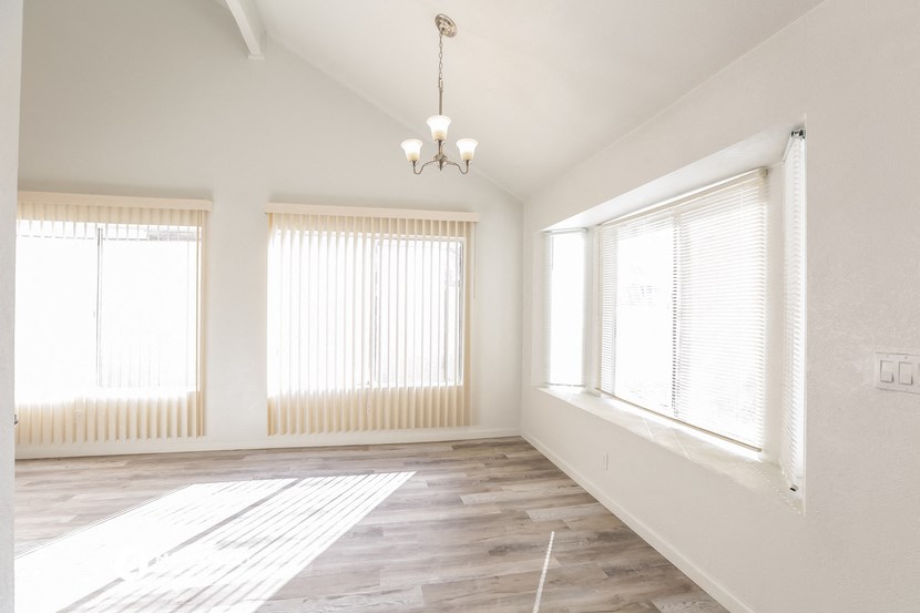 an empty living room with two windows and a chandelier