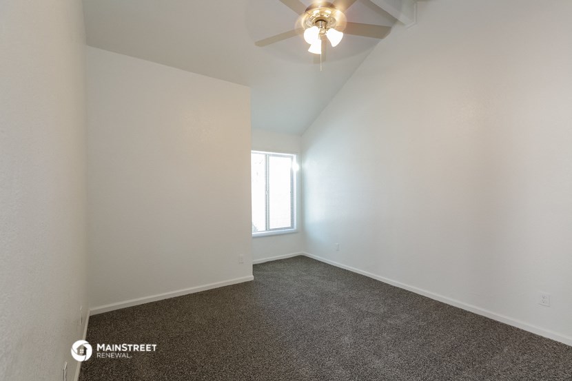 an empty room with a ceiling fan and a window