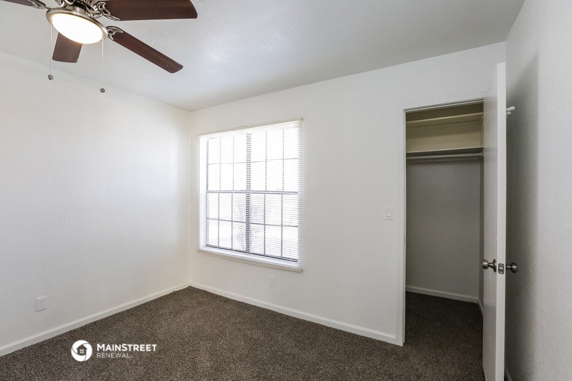 a bedroom with a ceiling fan and a door to a closet