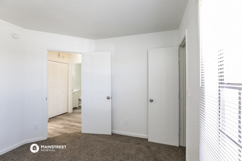 a bedroom with white walls and a door to a bathroom