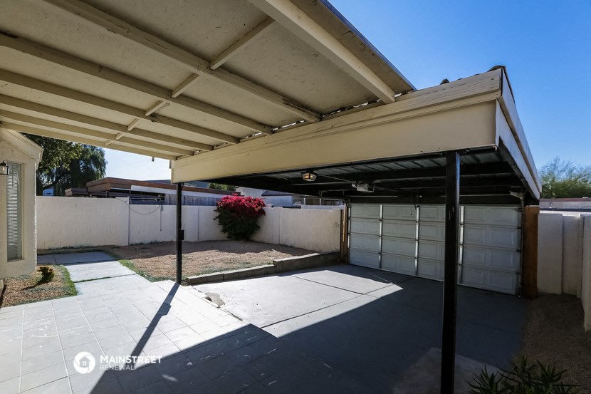 the driveway of a house with a white fence and garage doors