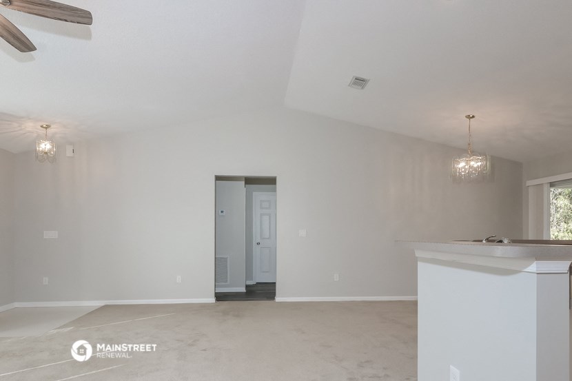 an empty living room with white walls and a white kitchen