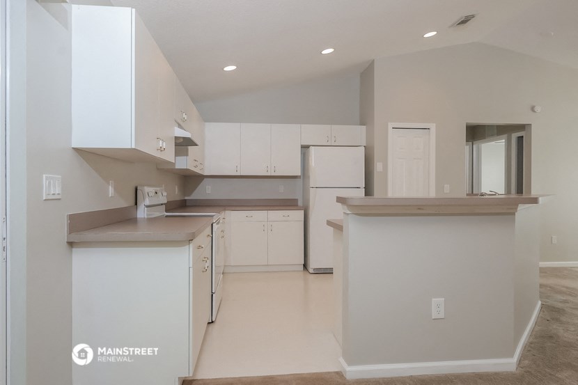 a kitchen with white cabinets and white counter tops and a refrigerator