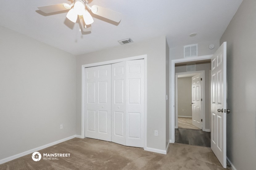 the living room of a manufactured home with white walls and a ceiling fan