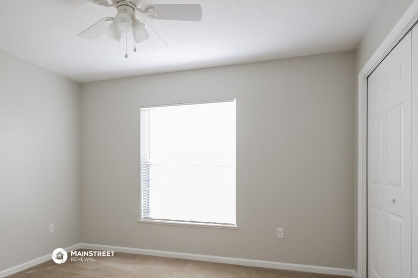 an empty room with a window and a ceiling fan