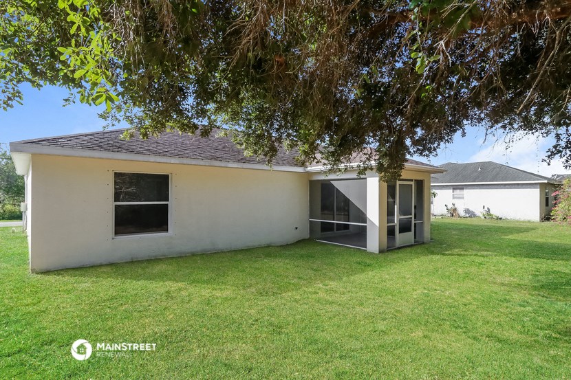 the backyard of a white house with a lawn and a tree