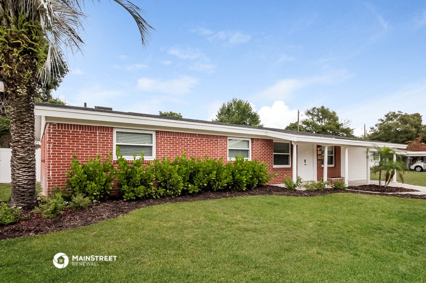 a brick house with a green lawn and a palm tree