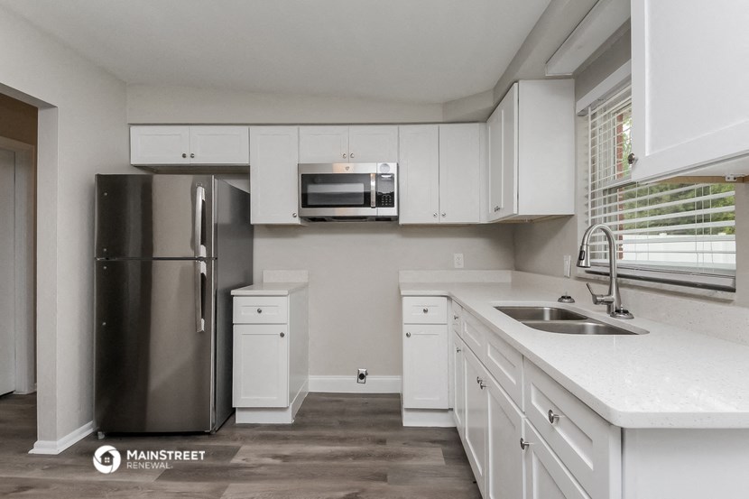 a kitchen with white cabinets and a stainless steel refrigerator