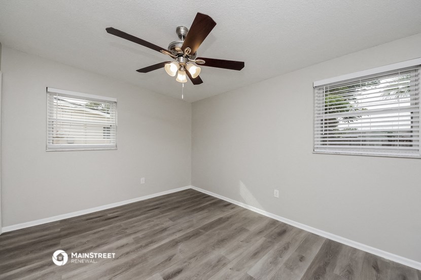 the spacious living room with ceiling fan and window