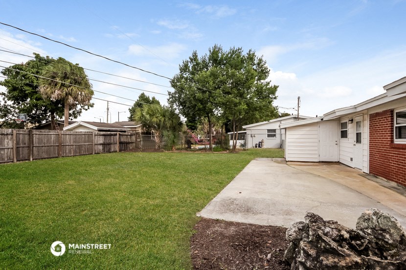 the backyard of a house with a yard and a concrete driveway